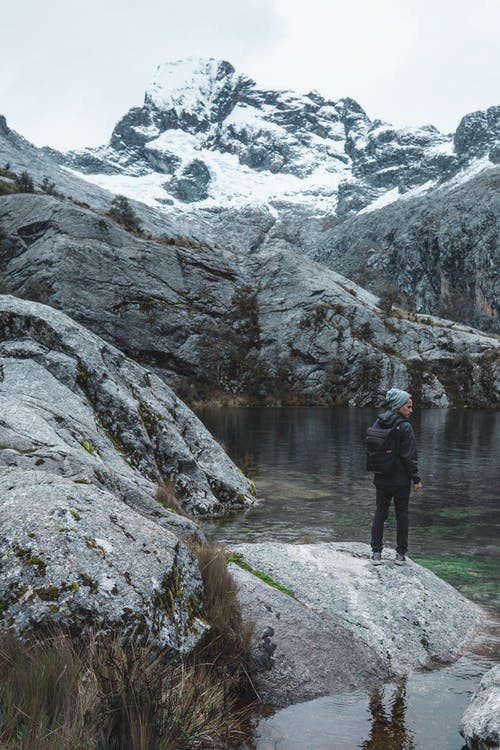 站在湖附近的灰色岩层上的人 · 免费素材图片