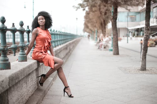 女人坐在混凝土砌块上的橙色礼服的选择性焦点照片 · 免费素材图片
