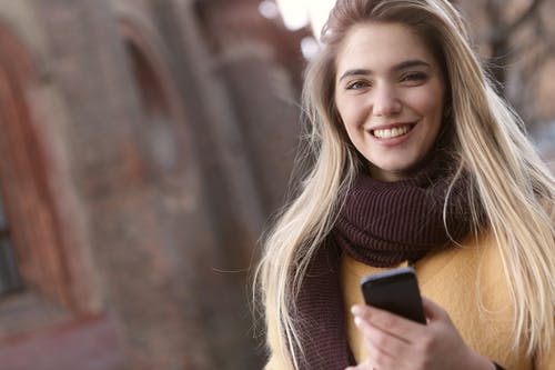浅焦点女人穿着棕色围巾时微笑的照片 · 免费素材图片
