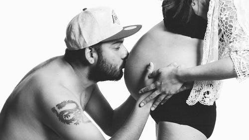 男人亲吻女人的孕妇铃铛的灰度摄影 · 免费素材图片