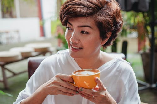 微笑的亚裔女子喝杯咖啡 · 免费素材图片