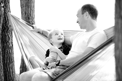 人和孩子坐在吊床上的灰度照片 · 免费素材图片
