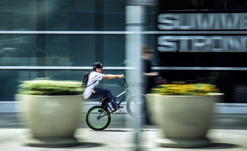男子骑自行车在城市 · 免费素材图片