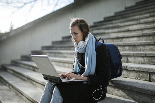 女人坐在混凝土楼梯上使用笔记本电脑 · 免费素材图片