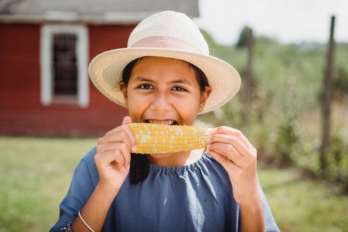 吃玉米的微笑的种族青少年的女孩在乡下 · 免费素材图片