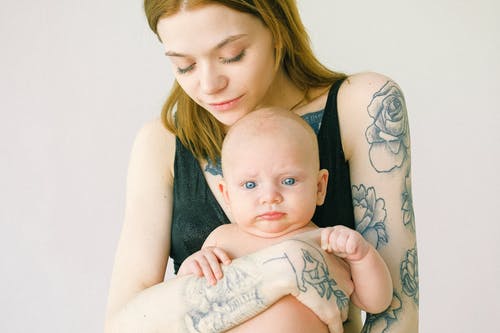 纹身的母亲抱着她可爱的婴儿 · 免费素材图片