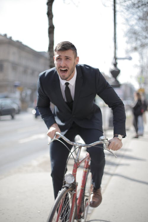 黑色西装外套的人在道路上骑红色自行车 · 免费素材图片