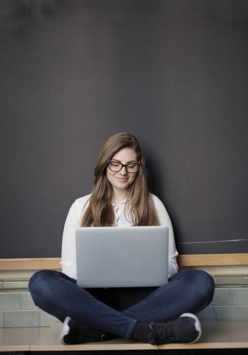 使用macbook的白色长袖衬衫和蓝色牛仔牛仔裤的女人 · 免费素材图片