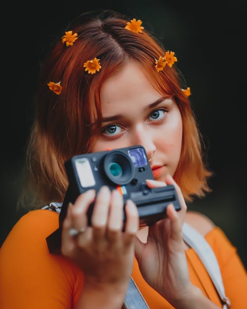 拿着照相机的橙色衬衣的妇女 · 免费素材图片