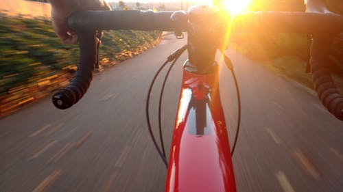 在日落期间骑在红色公路自行车上的人 · 免费素材图片