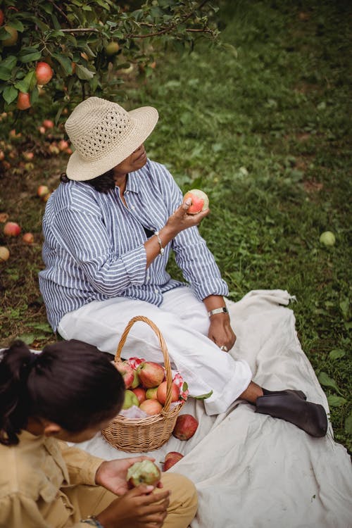 族裔母亲带着孩子在花园里野餐 · 免费素材图片
