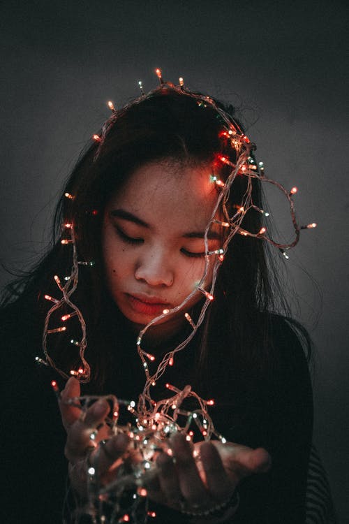 女人穿着黑色的长袖衬衫举行字符串灯 · 免费素材图片