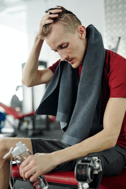 拿着瓶水的红色t恤的男人 · 免费素材图片