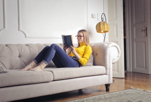 黄色长袖衬衫和蓝色牛仔牛仔裤，坐在白色的沙发上的女人 · 免费素材图片
