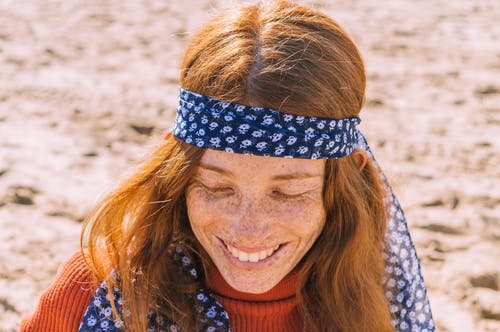 微笑的女人的肖像照片在橙色的高领毛衣和花卉头巾的雀斑 · 免费素材图片