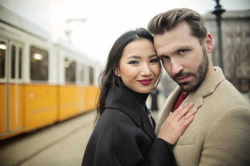 男人和女人站在黄色的火车旁边 · 免费素材图片
