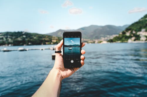 持有太空灰色iphone 5s拍海滩照片的人 · 免费素材图片
