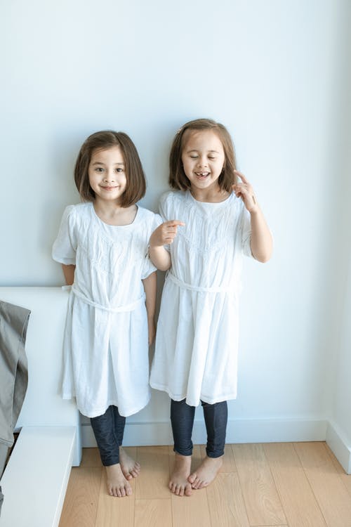 2站在白墙旁边的白衬衫的女孩 · 免费素材图片