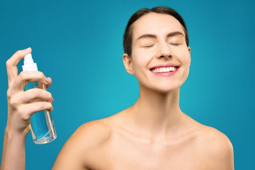 微笑的裸照女子捧着透明的玻璃瓶 · 免费素材图片