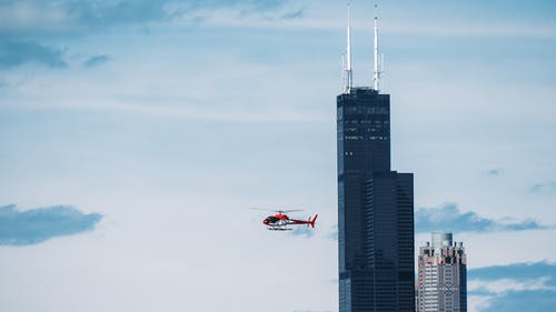 高层建筑背景下的直升机延时摄影 · 免费素材图片