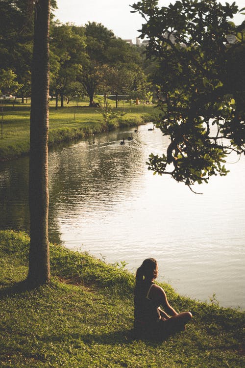 女人坐在湖边的草地上 · 免费素材图片