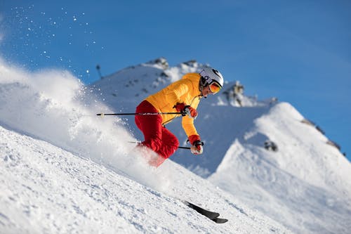 穿黄色夹克和红色裤子滑雪的人 · 免费素材图片