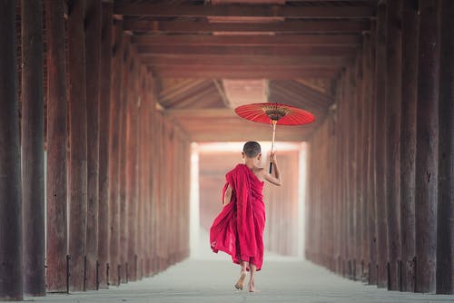 男孩拿着伞在木制框架之间行走 · 免费素材图片