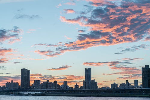 橙色和蓝色多云的天空下的城市天际线 · 免费素材图片