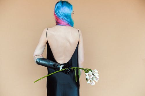 拿着白花的黑色意大利面条皮带礼服的女人 · 免费素材图片