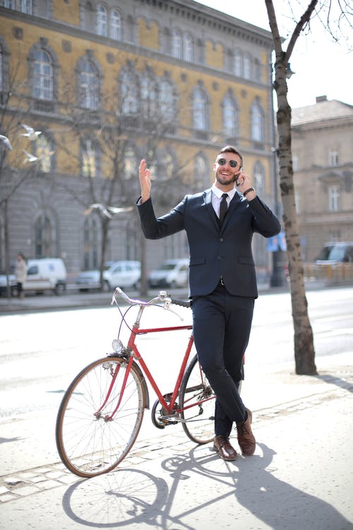 黑色西装外套和黑色的裤子，站在红色自行车旁边的人 · 免费素材图片