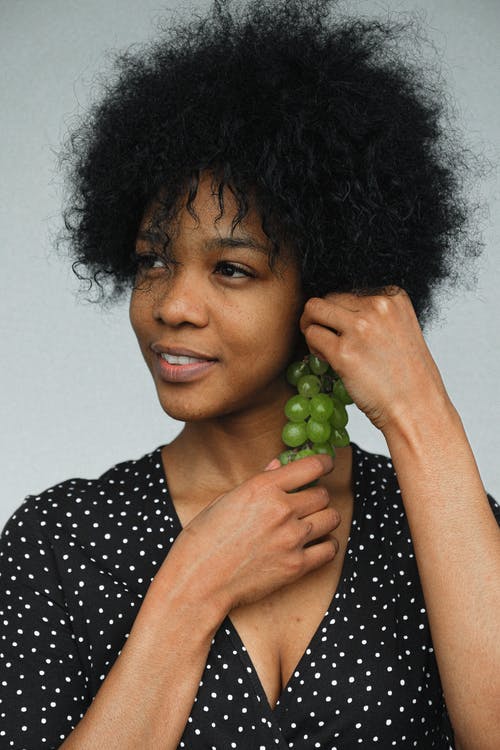 黑色和白色的圆点衬衫，拿着绿色水果的女人 · 免费素材图片