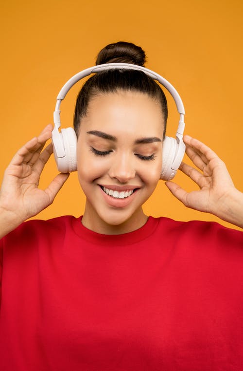 幸福的女人，在白色耳机上听音乐 · 免费素材图片