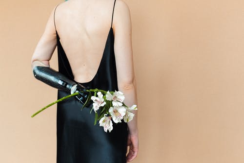 拿着白花的黑色意大利面条皮带礼服的女人 · 免费素材图片