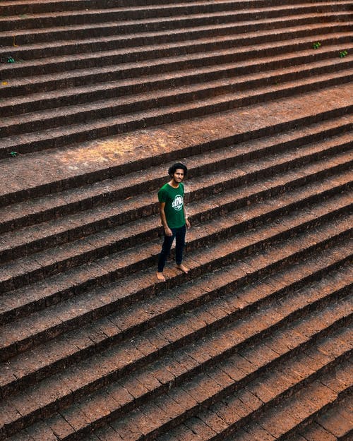 绿色衬衫站在棕色的混凝土楼梯上的男人 · 免费素材图片