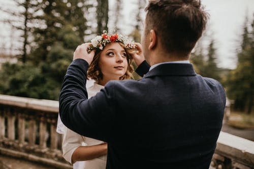 把皇冠花放在女人头上的黑色西装的男人 · 免费素材图片