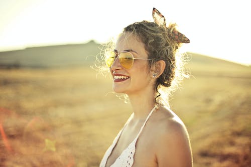 选择性聚焦侧视图微笑的女人，在白顶戴飞行员太阳镜的照片 · 免费素材图片