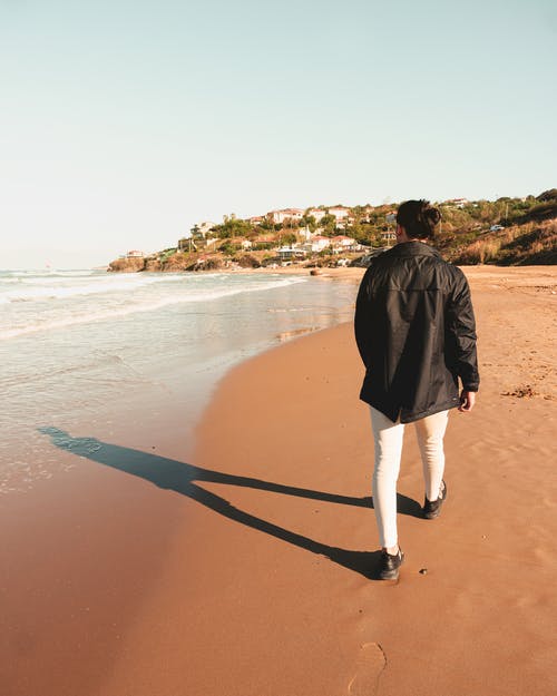 黑色外套和白色的裤子，在海滩上行走的人 · 免费素材图片