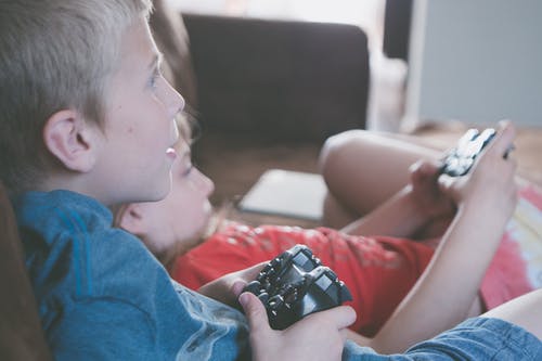 两个男孩和女孩抱着游戏控制器 · 免费素材图片