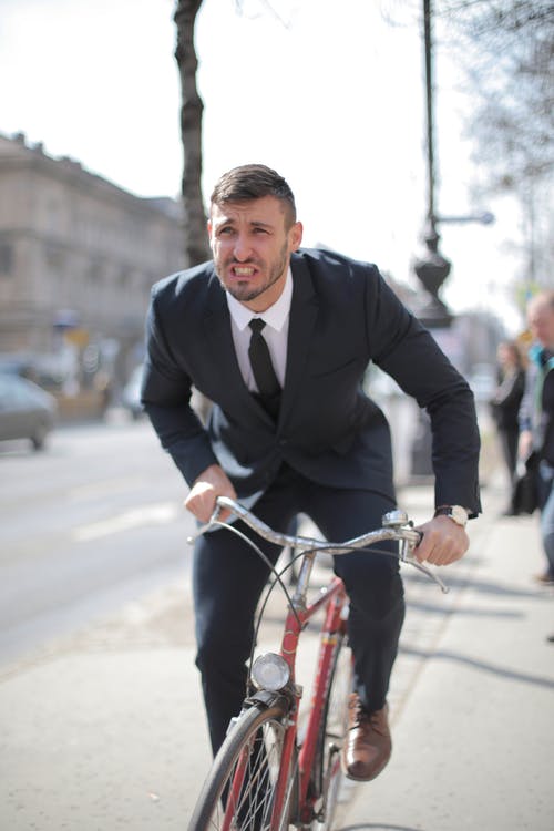 黑色西装外套的人在道路上骑红色自行车 · 免费素材图片