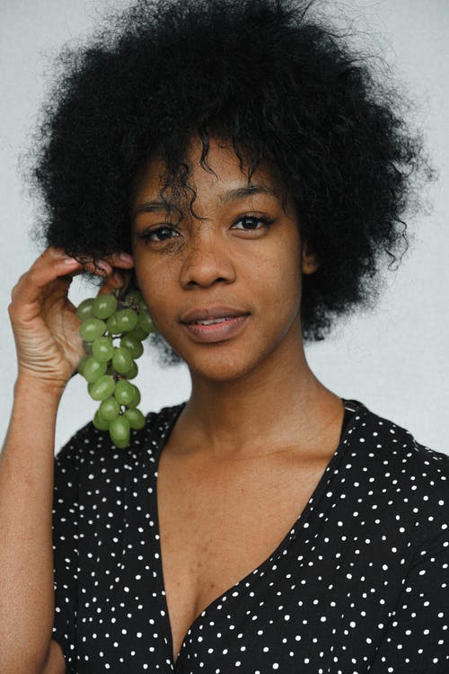 黑色和白色的圆点勺子领衬衫，拿着绿色的葡萄的女人 · 免费素材图片