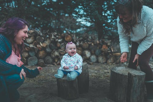 微笑的婴儿坐在砍下的树日志 · 免费素材图片