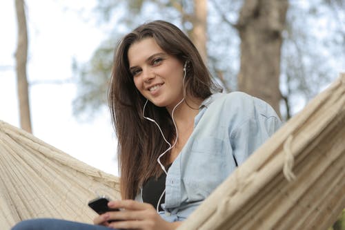 女人坐在吊床上边听音乐 · 免费素材图片