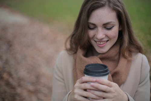 微笑的女士拿着黑色和白色的一次性杯子 · 免费素材图片