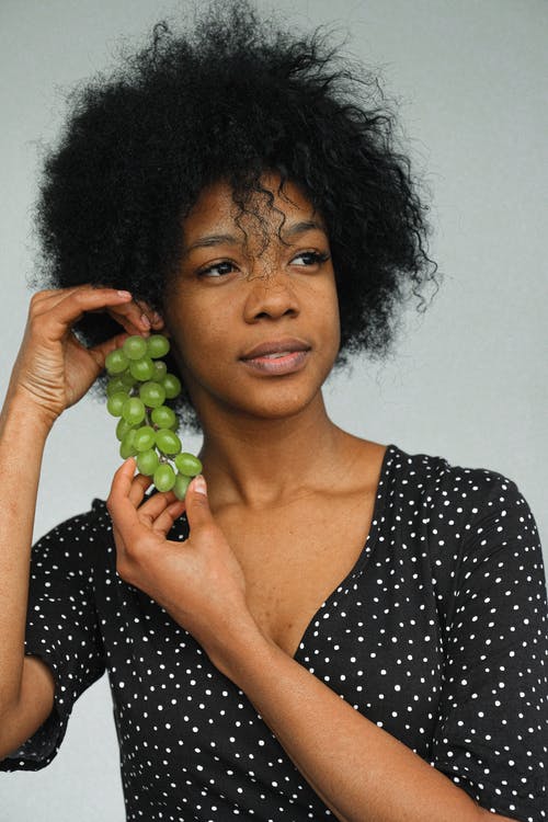 黑色和白色的圆点勺脖子衬衫拿着绿色水果的女人 · 免费素材图片
