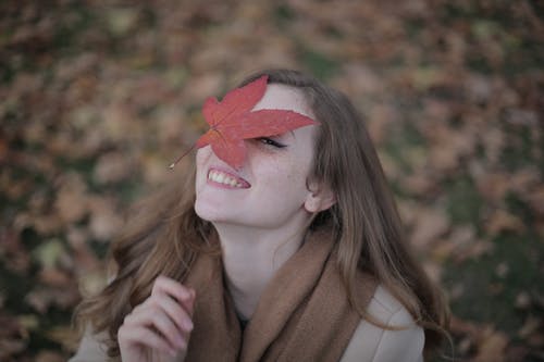 棕色外套的女人，她脸上的红枫叶 · 免费素材图片