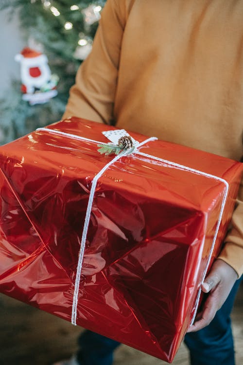 黑人携带有礼物的明亮的红色箱子在发光的包裹 · 免费素材图片