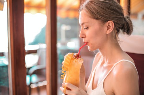 白色背心喝橙汁的女人 · 免费素材图片
