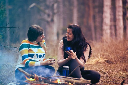 两个女人坐在篝火旁的地上 · 免费素材图片