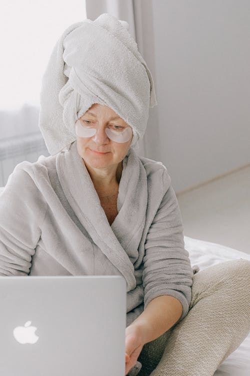 坐在床上的灰色浴袍的女人 · 免费素材图片
