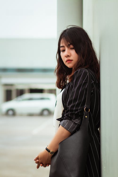 女人靠在墙上的选择性焦点摄影 · 免费素材图片